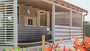A covered outdoor area with a wooden bench, a small table, and a chair. - Gotha Beach Srl - Casetta Lavanda (Ladispoli)