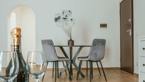 A dining area with a marble table, two grey chairs, a bottle of champagne, and glasses.