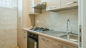 A modern kitchen with a gas stove, stainless steel sink, wooden cabinets, and a window.