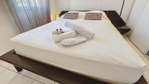 A neatly made bed with white linens, two decorative pillows, and a set of towels. - Apartment  by Interhome (Cannes)