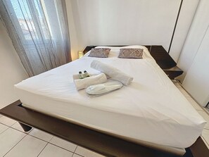 A neatly made bed with white linens, two decorative pillows, and a set of towels. - Apartment  by Interhome (Cannes)