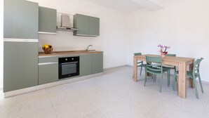 Una cucina moderna con forno integrato, un tavolo da pranzo con sedie e un vaso con fiori sul tavolo.