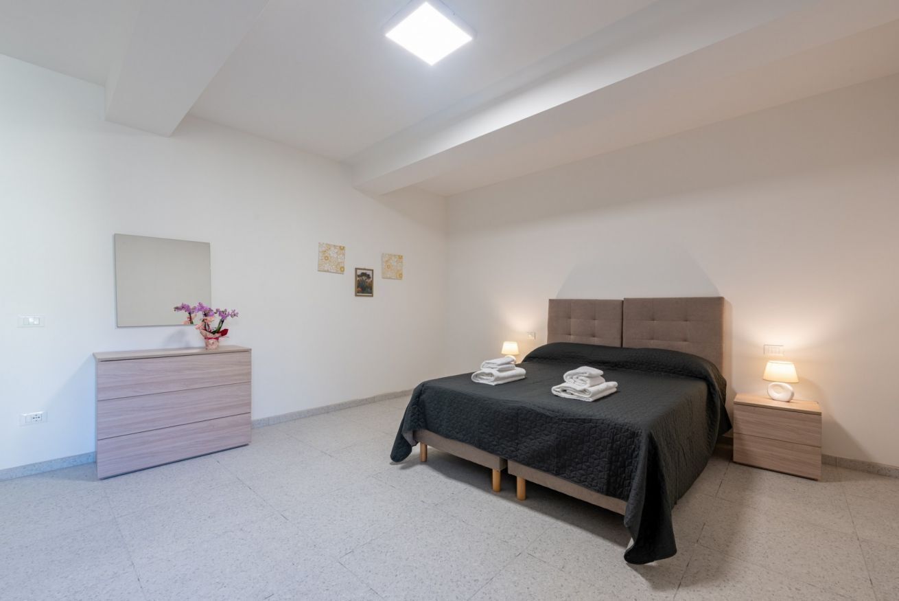A bedroom with a bed, bedside tables, a dresser, a mirror, and wall art.