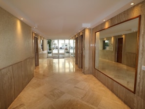 A hotel corridor with a polished floor, mirrored walls, and doors leading to rooms. - Amazing sea view 2 bedroom front of the beach 303 by Interhome (Cannes)