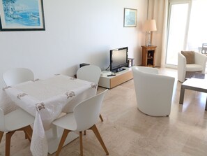 A modern living room with a dining area, a flat-screen TV, and a lamp. - Amazing sea view 2 bedroom front of the beach 303 by Interhome (Cannes)
