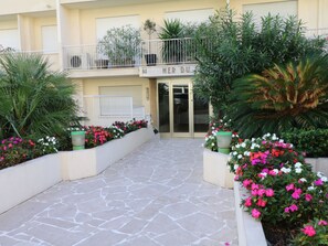 A hotel entrance with a stone-paved walkway, potted plants, and a sign above the door. - Amazing sea view 2 bedroom front of the beach 303 by Interhome (Cannes)