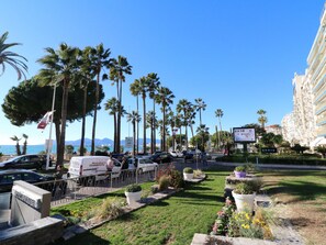 A coastal hotel with a view of the sea, palm trees, and a parking area with cars. - Apartment  by Interhome (Cannes)