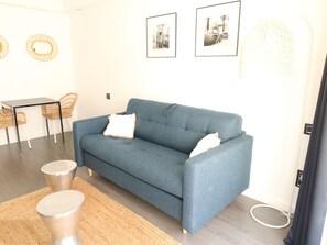 A modern living room with a blue sofa, two chairs, a small table, and a woven rug. - Apartment  by Interhome (Cannes)
