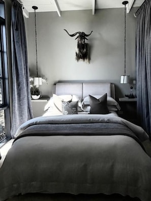 Una camera da letto moderna con un letto grande, una testiera, comodini e una lampada a sospensione.