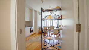 Une cuisine moderne avec des meubles blancs, une table à manger en bois et un luminaire suspendu.