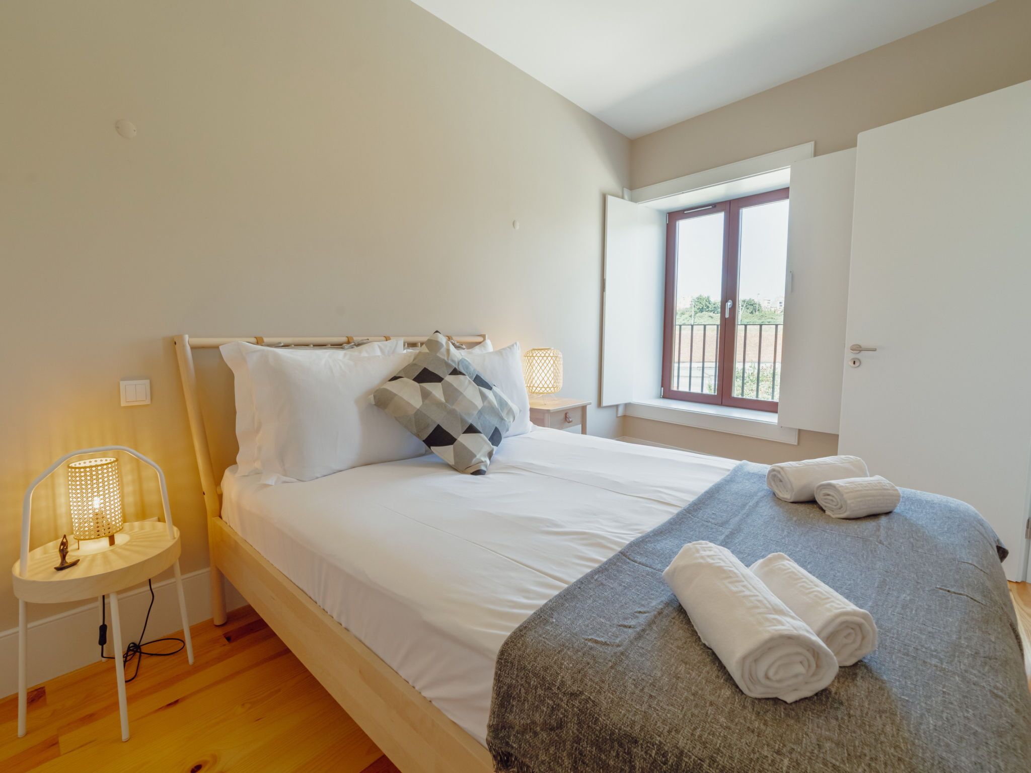 Une chambre à coucher avec un lit, des lampes de chevet, une fenêtre et une porte.