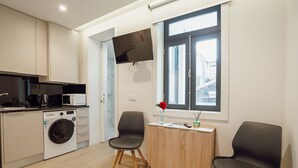 Eine moderne Küche mit Geräten, einer Waschmaschine und einem Essbereich mit zwei Stühlen und einem Tisch.