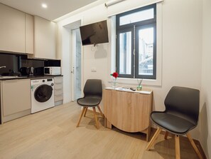 Eine moderne Küche mit Geräten, einer Waschmaschine und einem Essbereich mit zwei Stühlen und einem Tisch.