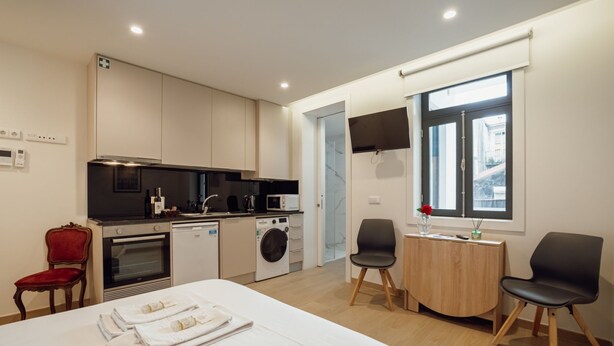 Ein modernes Hotelzimmer mit Bett, Essbereich, Küche und Bad.