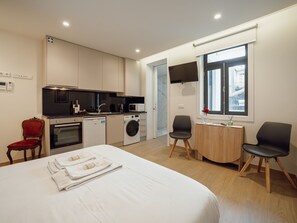 Ein modernes Hotelzimmer mit Bett, Essbereich, Küche und Bad.