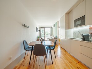 Une cuisine moderne avec un coin repas, un plancher en bois et une vue sur l’extérieur.