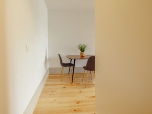 Ein schmaler Flur mit Holzboden führt zu einer kleinen Essecke mit zwei Stühlen und einem Tisch.