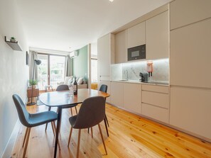 A modern kitchen with a dining area, wooden flooring, and a view to the outside. - Apartment  by Interhome (Porto)