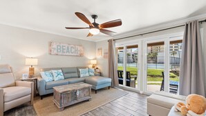 A living room with a sofa, armchairs, a coffee table, a ceiling fan, and a large sliding glass door leading to an outdoor area. - 2BR Condo Ground Floor Beach Access Pool Sleeps 6 (Panama City Beach)