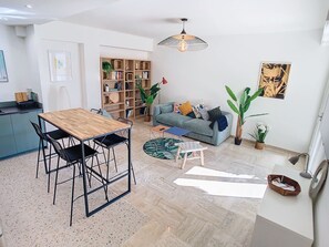 Ein modernes Wohnzimmer mit einem Holzes Esstisch, schwarzen Stühlen, einem blauen Sofa und einem großen Bücherregal.