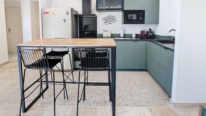 Eine kleine Küche mit Holztisch und zwei Stühlen, einer Mikrowelle und einem Kühlschrank.