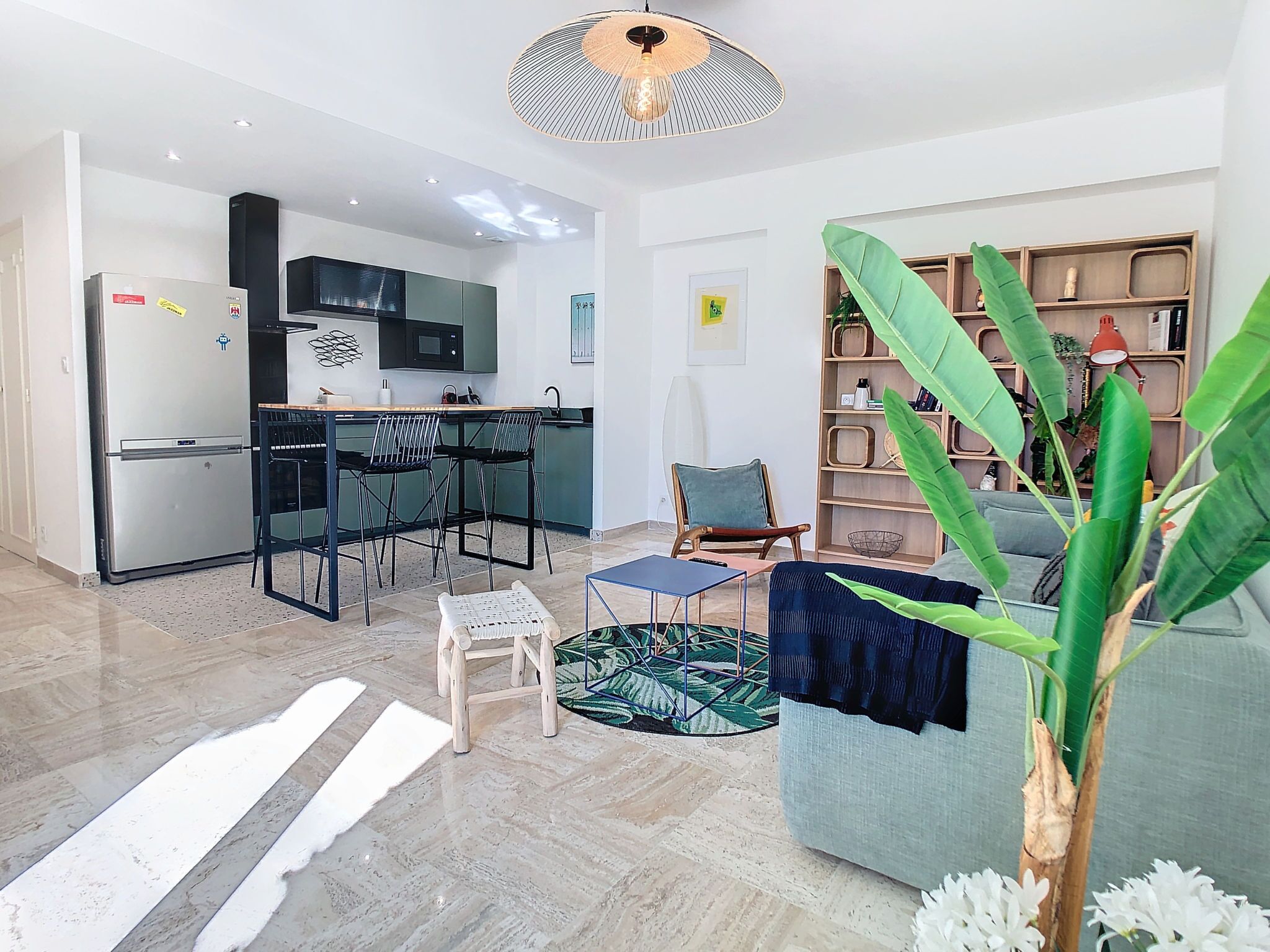 A modern living room with a sofa, a coffee table, and a dining area with chairs and a kitchen in the background.