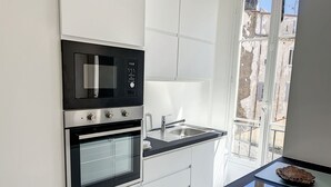 Una cocina moderna con horno empotrado, microondas y pileta de acero inoxidable.