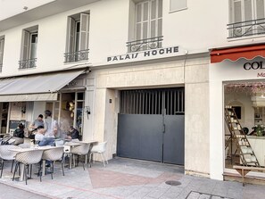 A cafe with outdoor seating, a closed metal gate, and a storefront with a sign. - 1 bedroom Palais Hoche Cannes Riviera 226 by Interhome (Cannes)