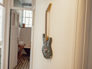 A guitar hanging on a wall in a room with a checkered floor and a window. - Apartment  by Interhome (Porto)