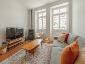 Ein modernes Wohnzimmer mit Fernseher, Sofa und Kamin.