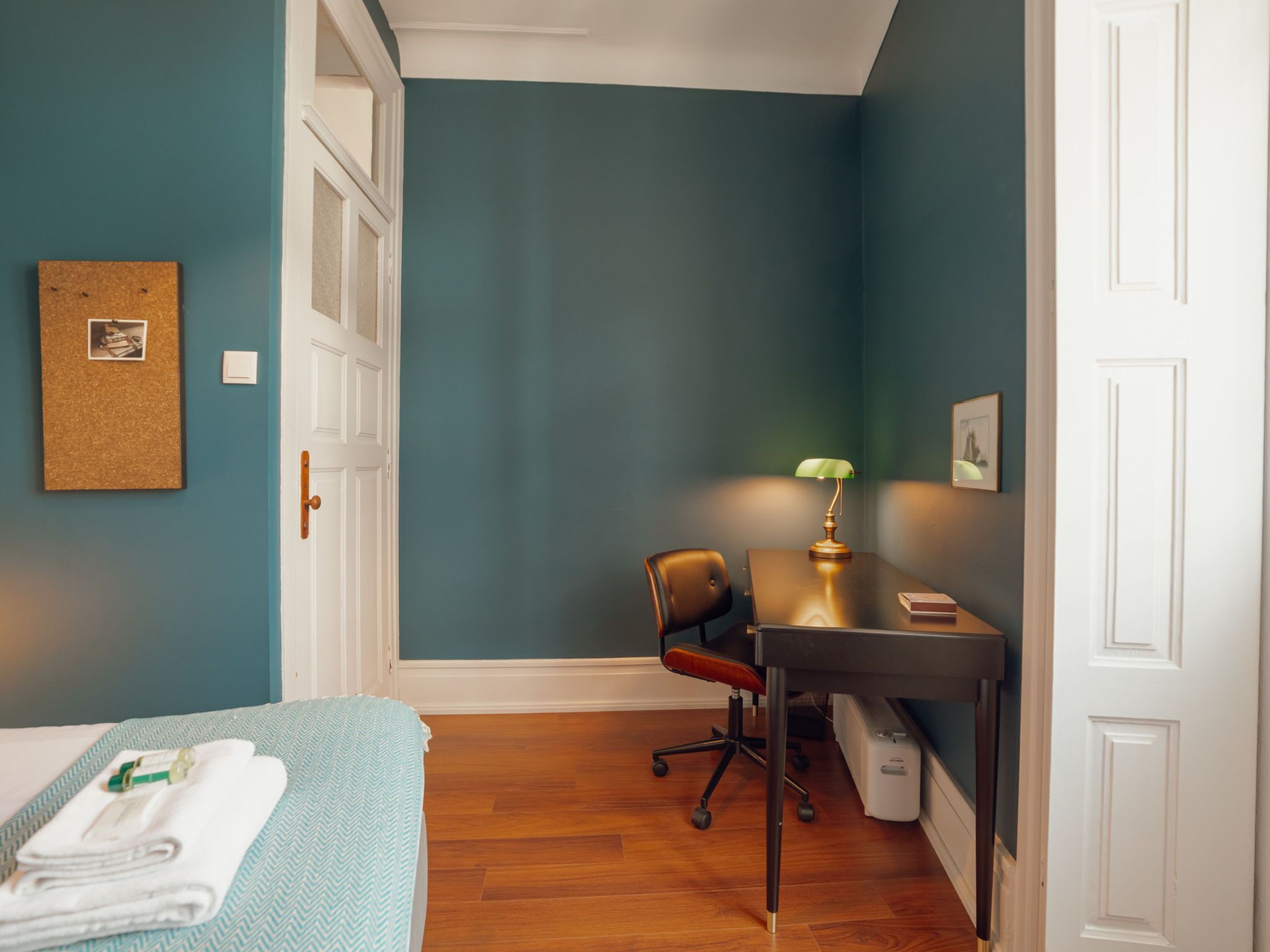 A room with a bed, a desk, a chair, and a lamp.