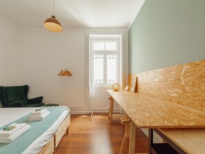 A bedroom with a bed, a desk, a hanging lamp, and a window. - Apartment  by Interhome (Porto)