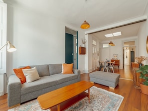 Un salon moderne avec un canapé gris, une table basse en bois et un coin repas comprenant une table et des chaises.