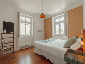 Ein Schlafzimmer mit einem Bett, einer Hängelampe, einer Heizung, einer Holzleiter und einem Fernseher an der Wand.
