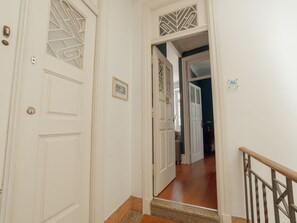 Un couloir avec des portes blanches, un tableau encadré au mur et un escalier menant à une autre pièce.