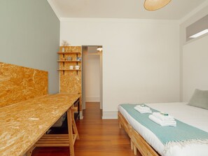 A bedroom with a wooden bed, a small desk, and a shelving unit with decorative items. - Apartment  by Interhome (Porto)