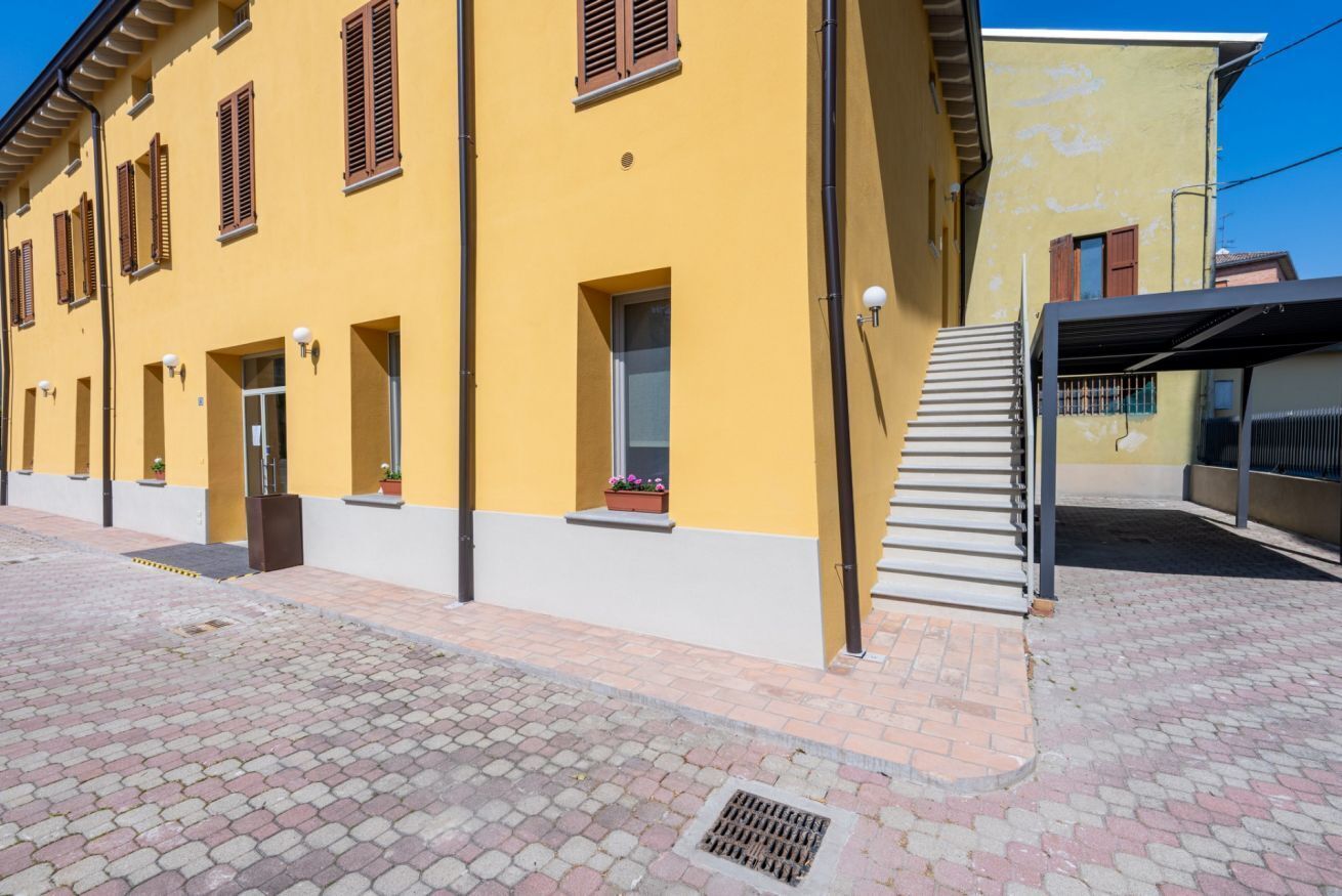 A yellow building with multiple windows and a covered entrance.