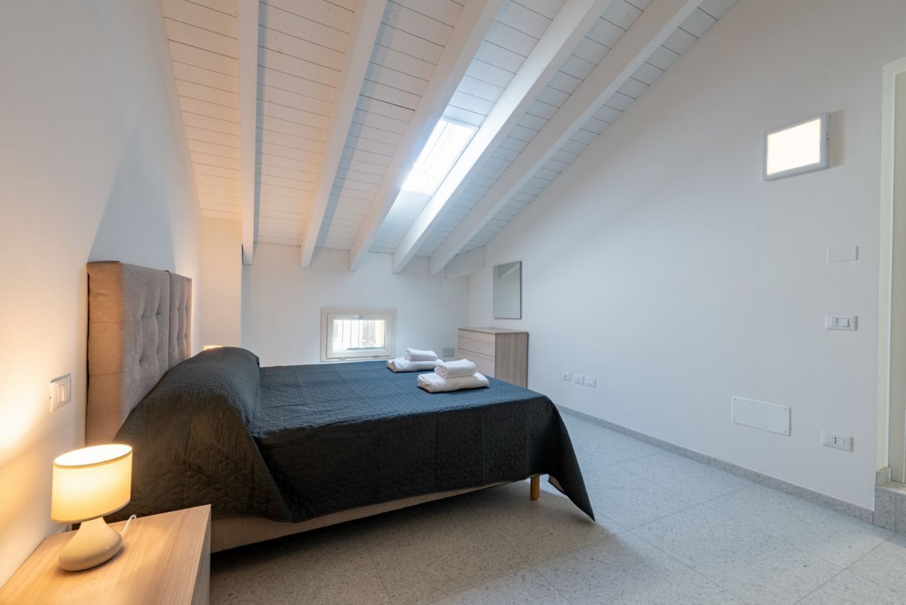 A bedroom with a bed, bedside lamp, and a window.