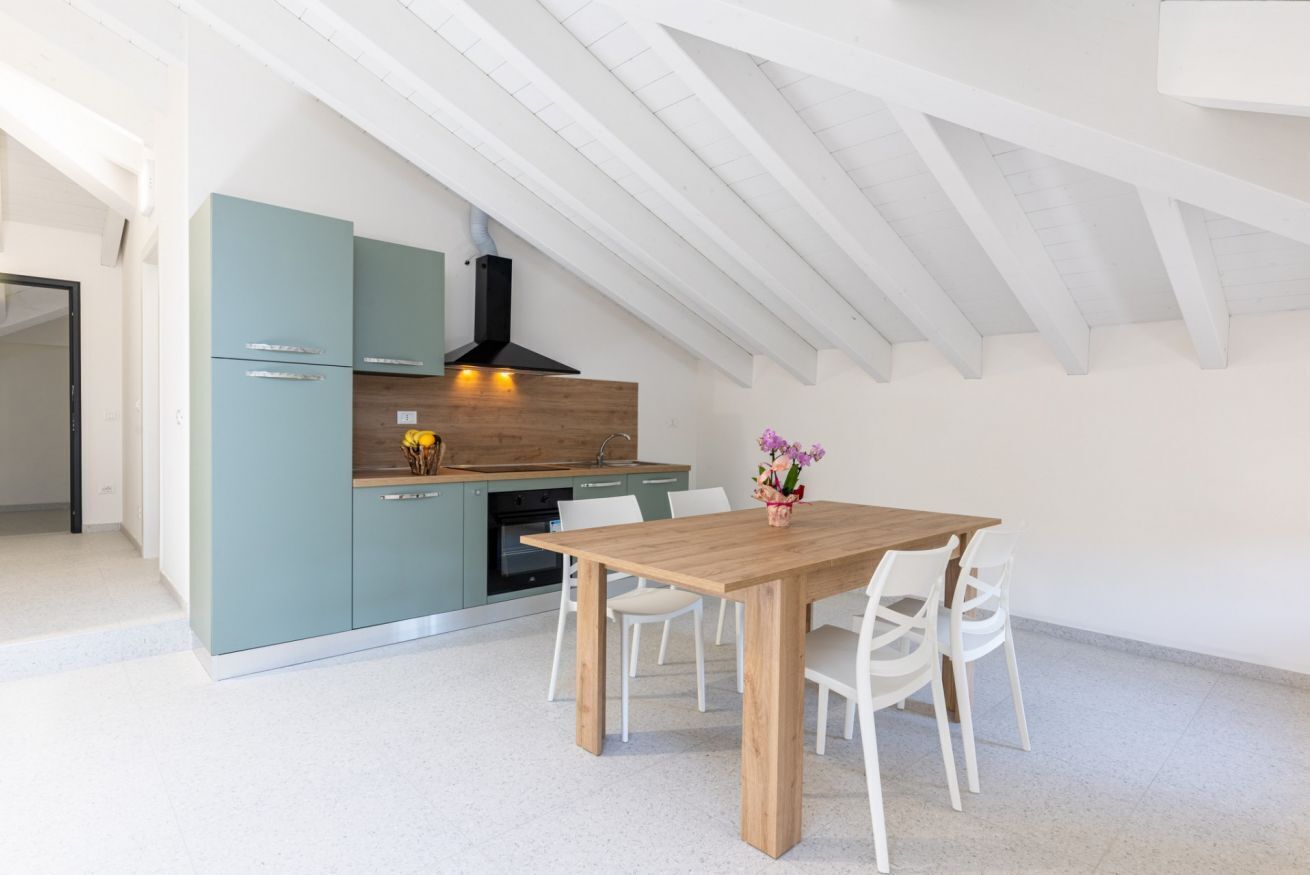 Een moderne keuken met een eetgedeelte, witte kasten en een houten tafel.