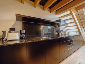 A modern kitchen with a stainless steel range hood, a built-in oven, and a coffee maker. - ELEGANT DOWNTOWN APARTMENT by VACATIONY by Interhome (Porto)