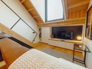 A loft-style bedroom with a sloped ceiling, a bed, a TV, and a small seating area. - ELEGANT DOWNTOWN APARTMENT by VACATIONY by Interhome (Porto)