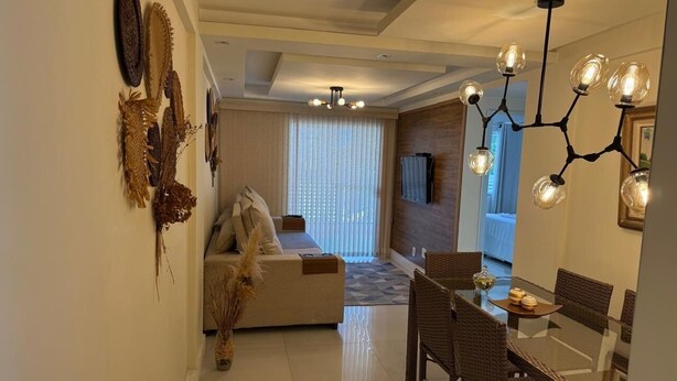 Una sala de estar moderna con sofá, mesa de comedor, sillas, una lámpara de araña y arte decorativo en las paredes.