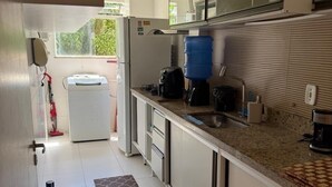 Una cocina moderna con gabinetes blancos, encimera de granito, un dispensador de agua grande y vistas al exterior.