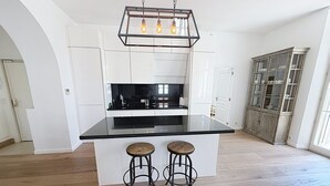 Una cucina con isola centrale, sgabelli da bar e lampadario a sospensione.