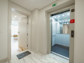 Ein Aufzug mit Glastür, einem roten Notausgangsschild und einem grünen Hinweisschild darüber.