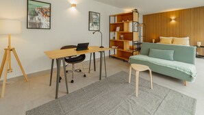 Una sala de estar moderna con un escritorio, un sofá, una estantería y una lámpara.
