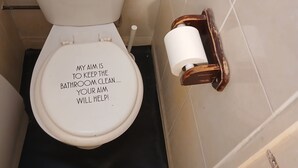 A bathroom with a toilet, a bidet, and a toilet paper holder. - Room-room in a Family House (Grays)