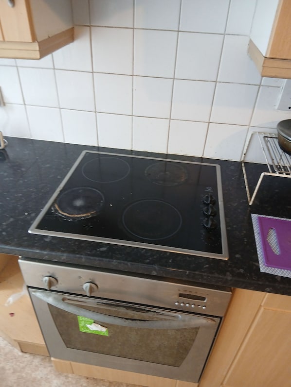 Eine Küche mit Herd, Backofen und einer gefliesten Spritzschutzwand.