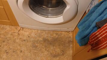A top-down view of a ProAction washing machine with a front-loading door, a control panel with various settings, and a green 'A+' rating sticker.