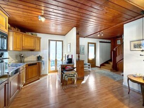 A spacious kitchen with wooden cabinets, a dining area with a table and chairs, and a staircase leading to another level. - Chalet l'Escapade - 6 to 10 pax - Swiss Alps by Interhome (Salvan)